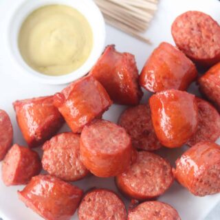 cooked polska kielbasa in air fryer on a plate with mustard and toothpicks