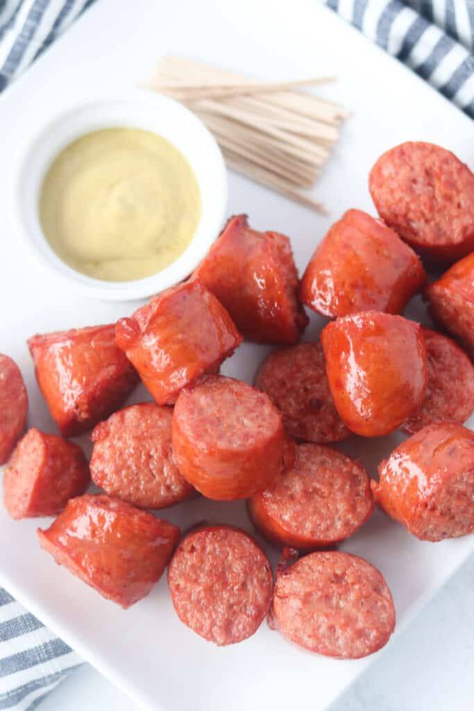 cooked polska kielbasa in air fryer on a plate with mustard and toothpicks