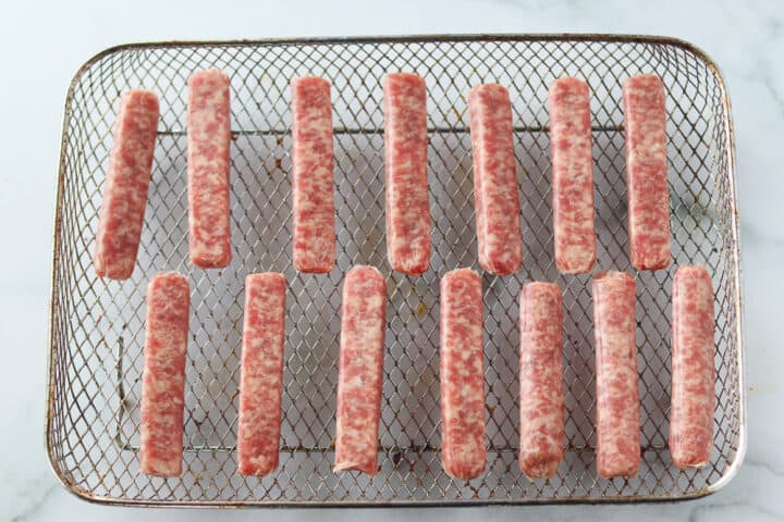 sausage links in air fryer ready to be cooked on a pan