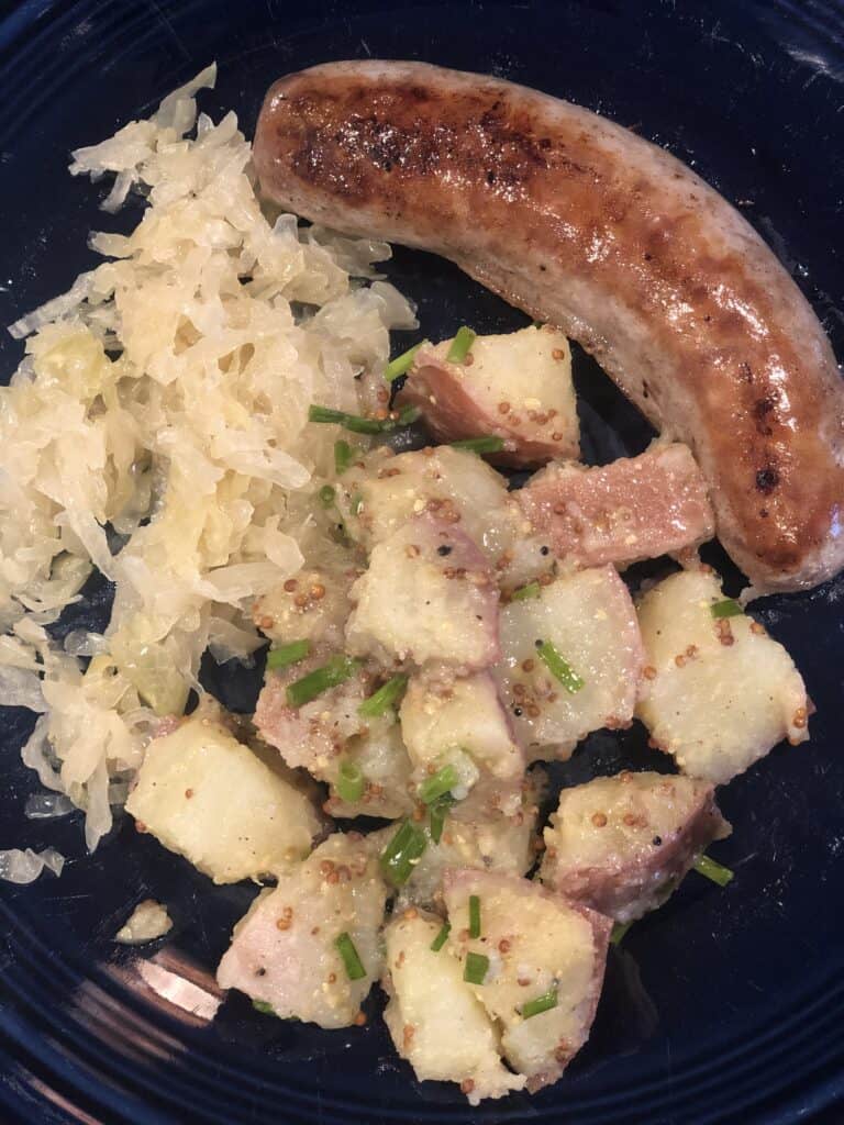 sides for brats on a plate including potato salad and sauerkraut