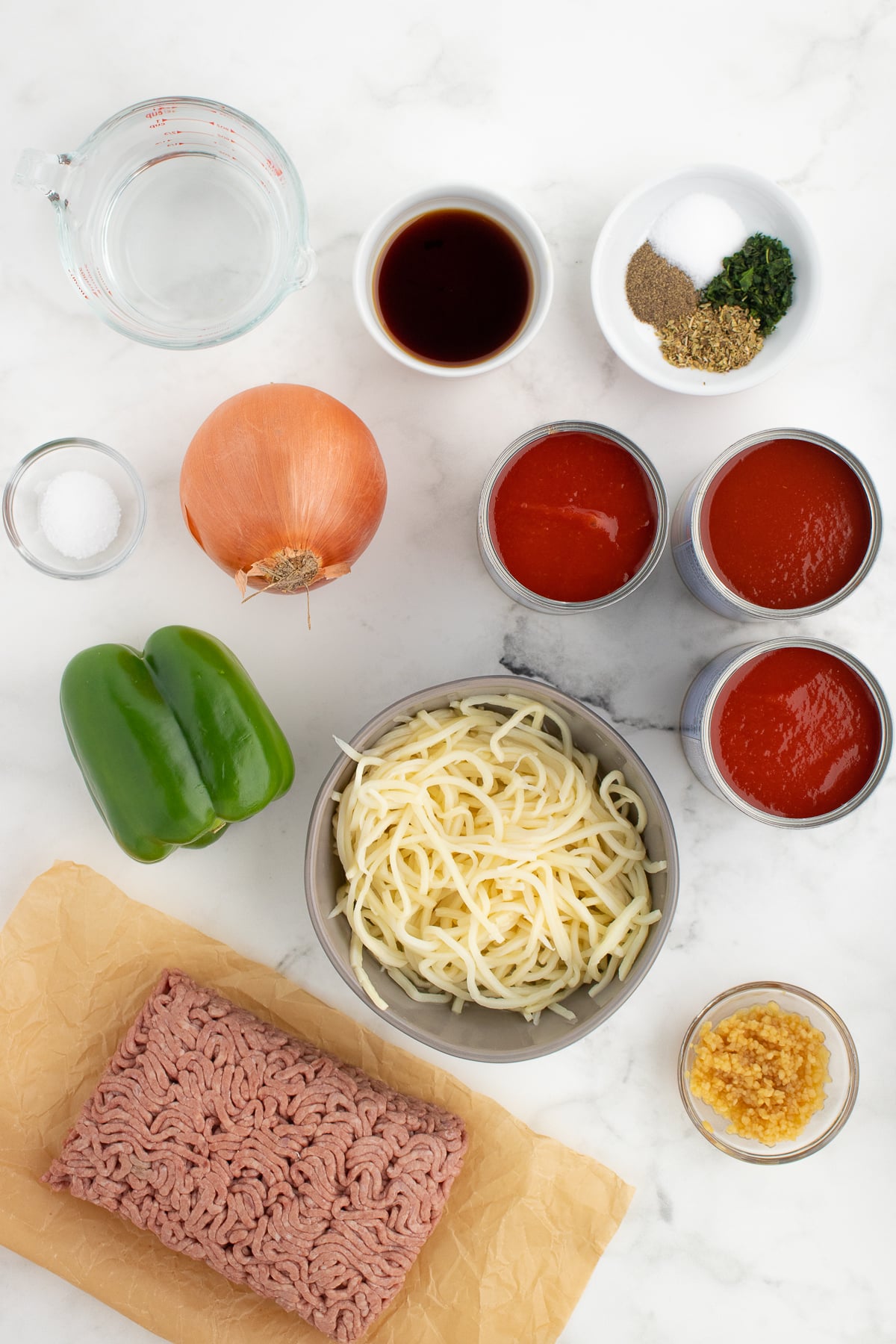 low carb spaghetti and meat sauce ingredients on a white cutting board