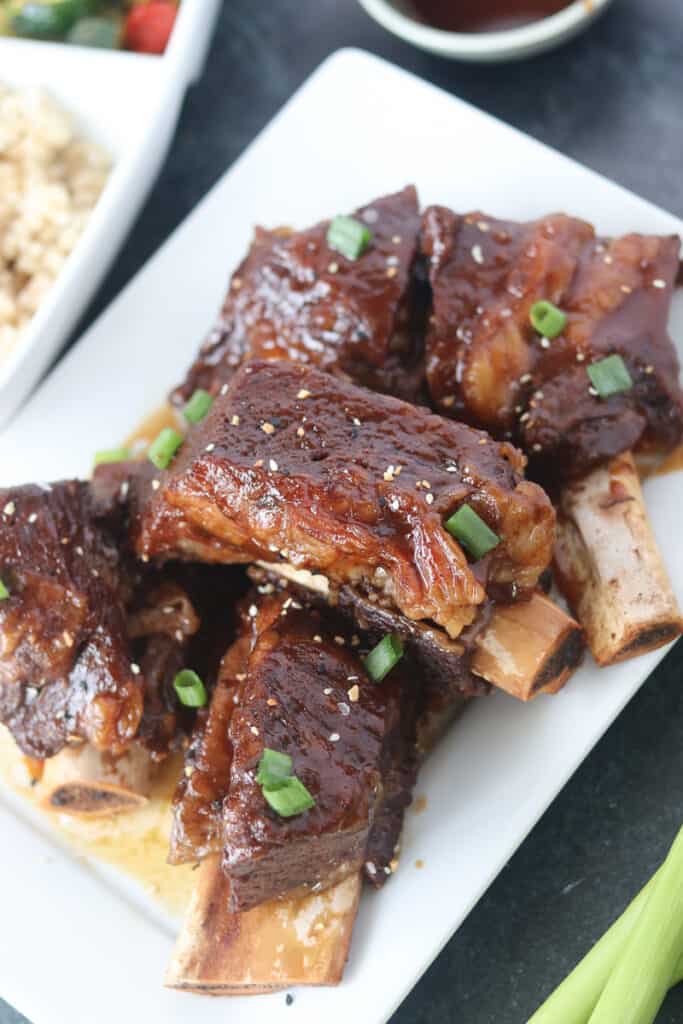 instant pot beef short rib on a platter with sides of rice and sauteed vegetables
