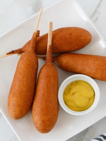 air fryer frozen corn dogs on a plate with mustard