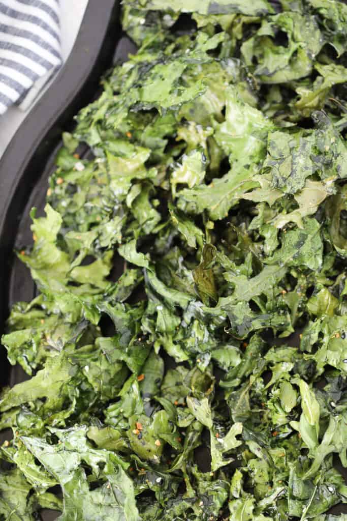 multiple batches of air fryer kale chips on a baking tray