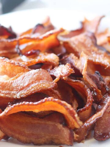 cooking bacon in air fryer on a white plate after it's done