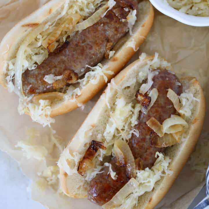 cooking brats in the oven served on buns with sauerkraut and onions