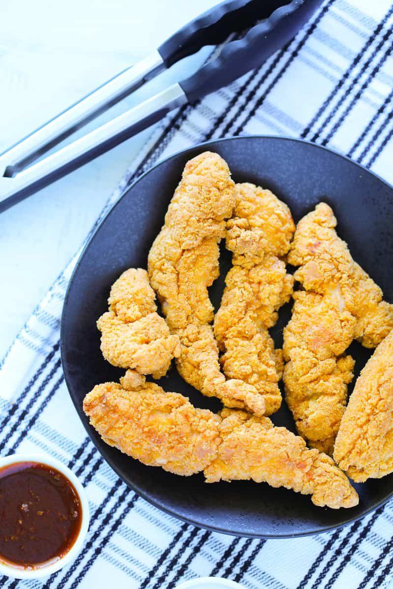 frozen chicken strips in air fryer on a black plate and white background