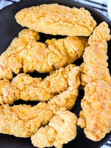 frozen chicken tenders in air fryer on a plate next to ketchup
