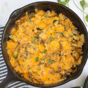 ground beef zucchini casserole in a skillet on a white background after cooking
