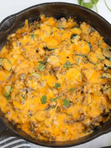 ground beef zucchini casserole in a skillet on a white background after cooking
