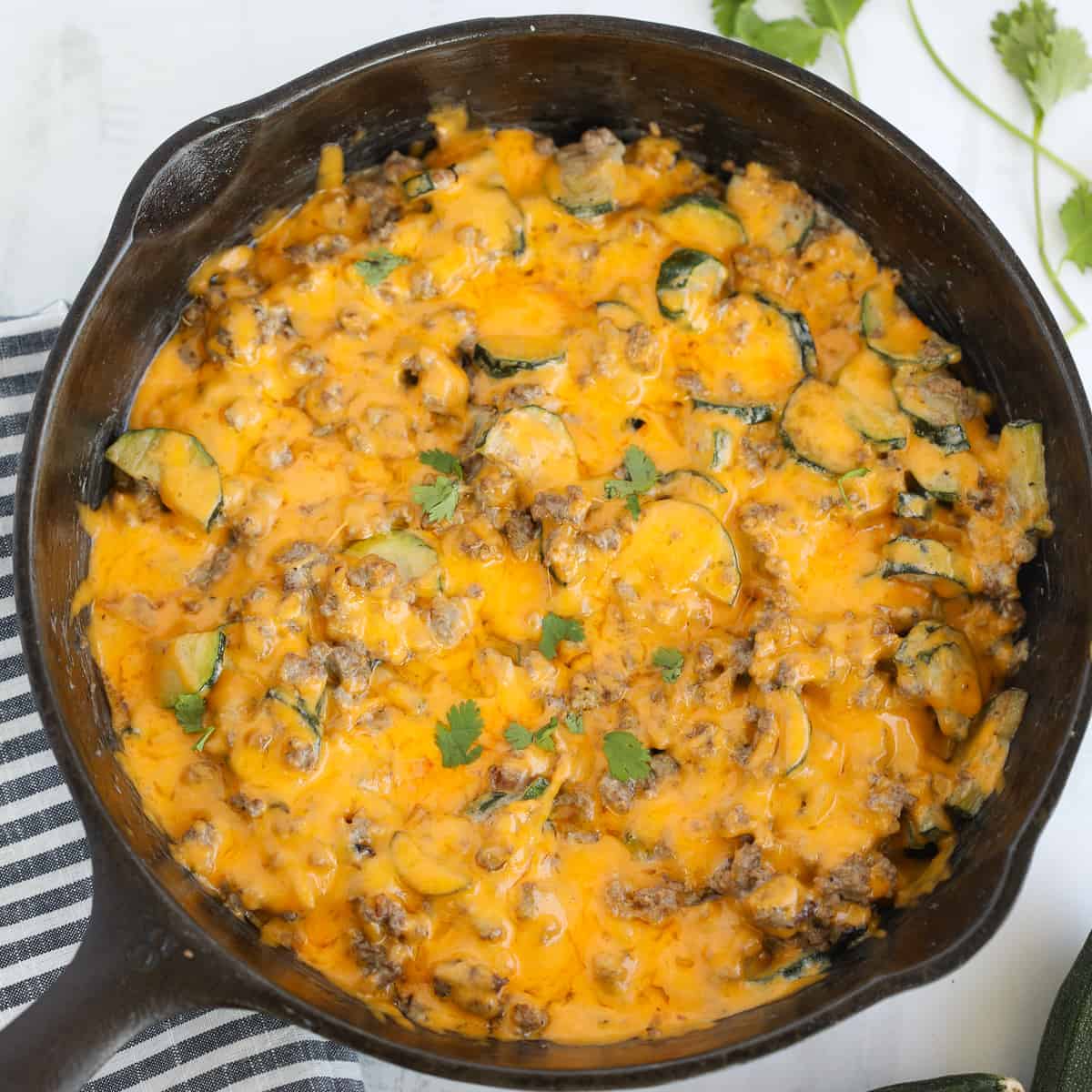 ground beef zucchini casserole in a skillet on a white background after cooking