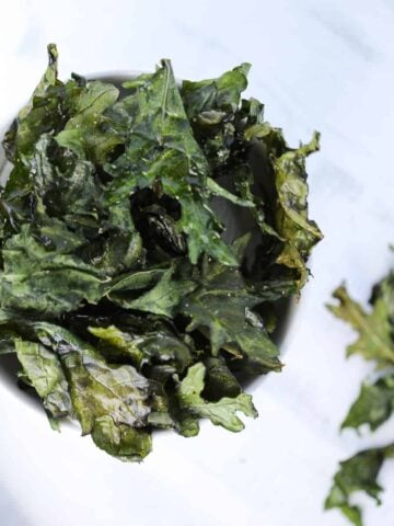 kale chips in air fryer recipe after cooking displayed in a white bowl