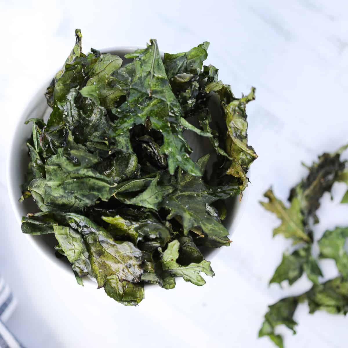 kale chips in air fryer recipe after cooking displayed in a white bowl