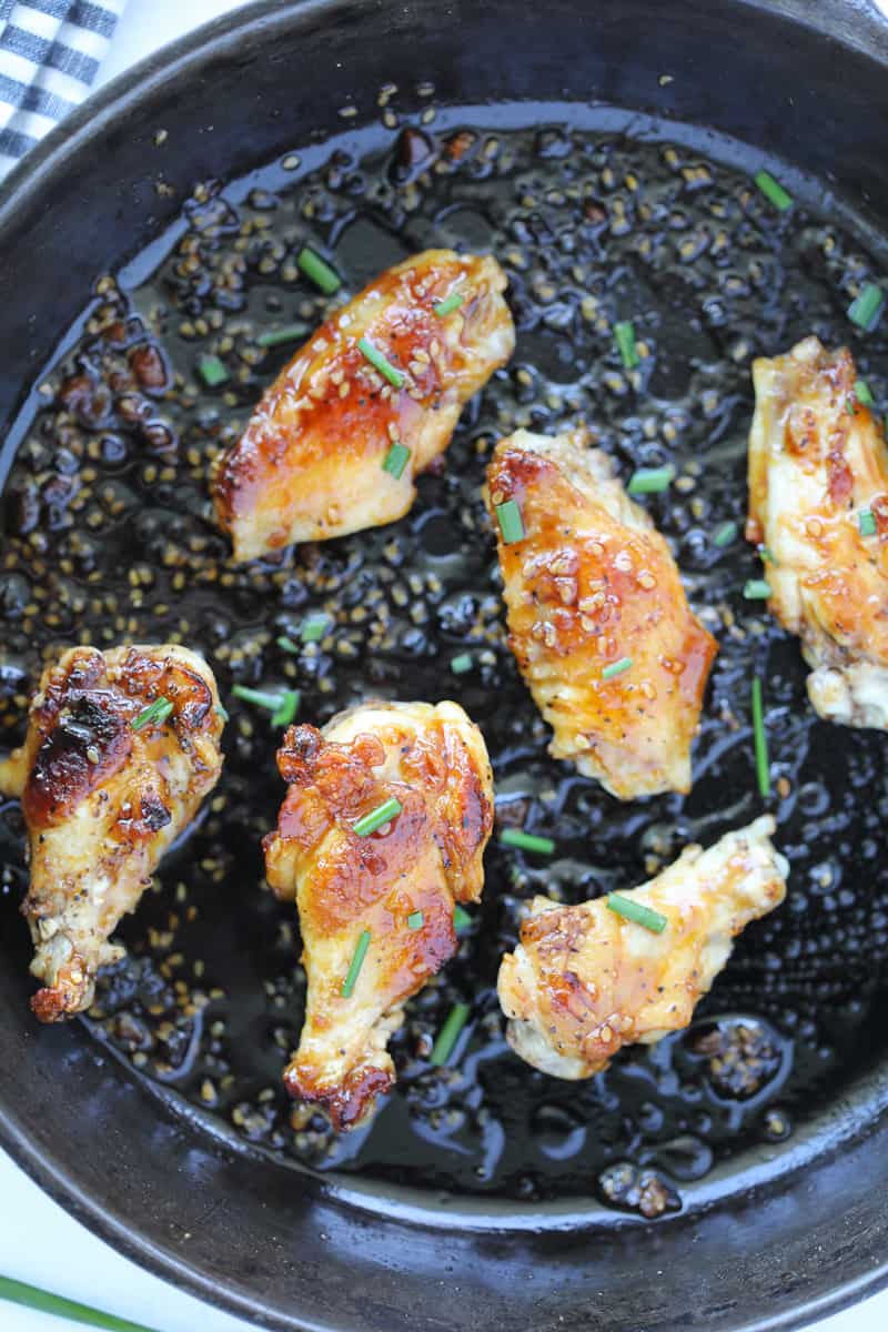 pan fry chicken wings with teriyaki sauce in a skillet and chive garnish