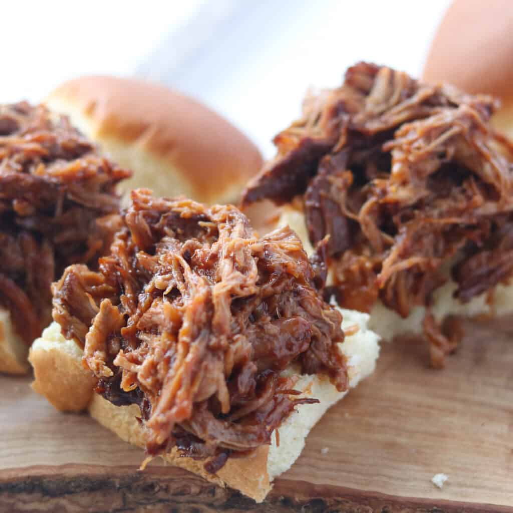 photo of pulled pork Hawaiian rolls with top bun laying on the side