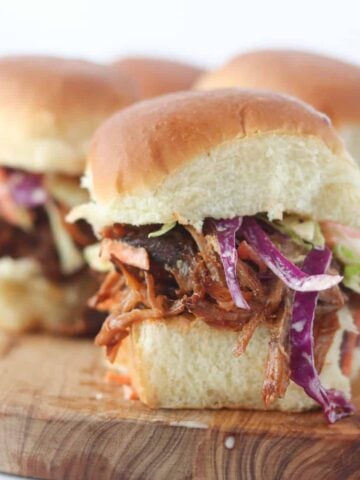pulled pork sliders on hawaiian rolls displayed on a cutting board