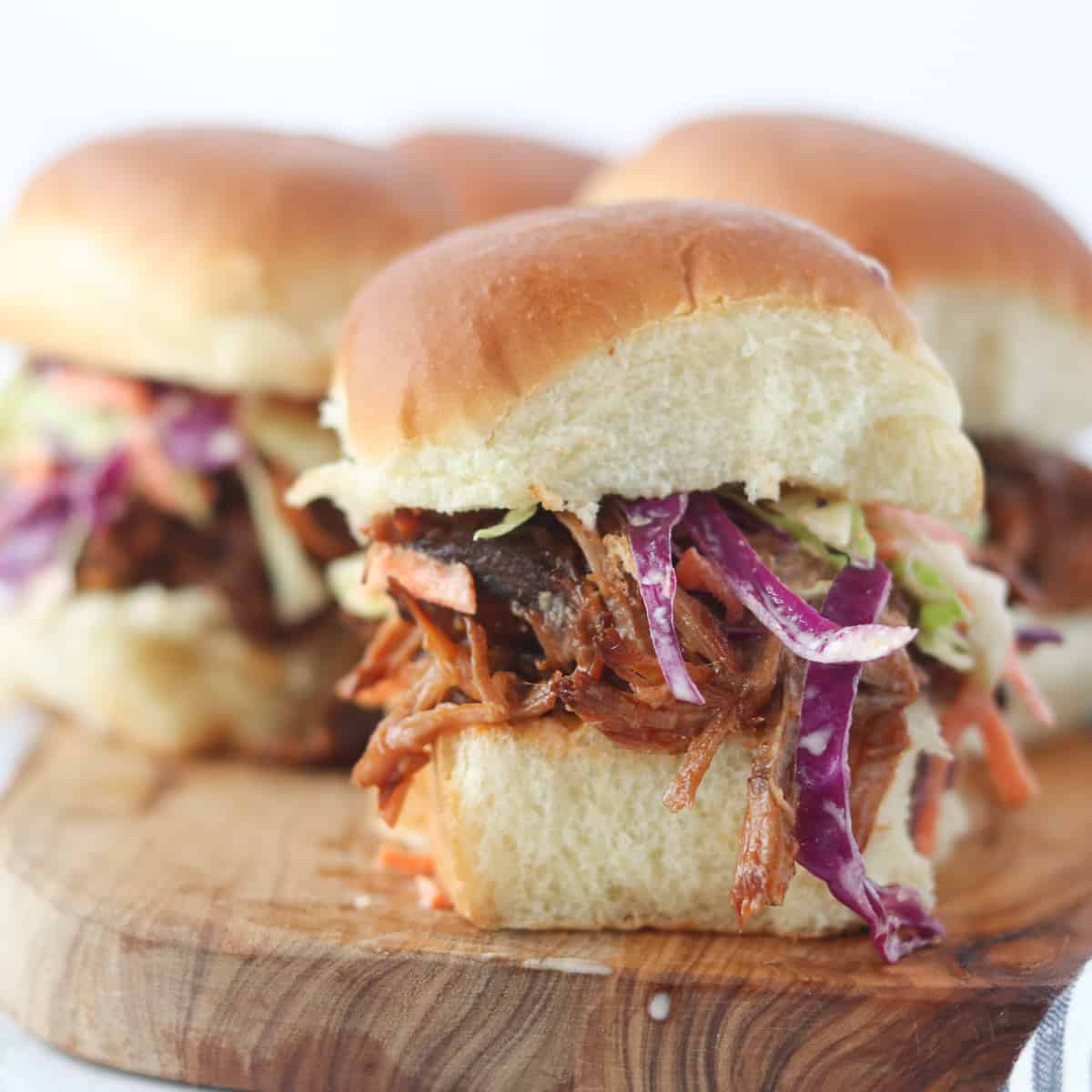 pulled pork sliders on hawaiian rolls displayed on a cutting board