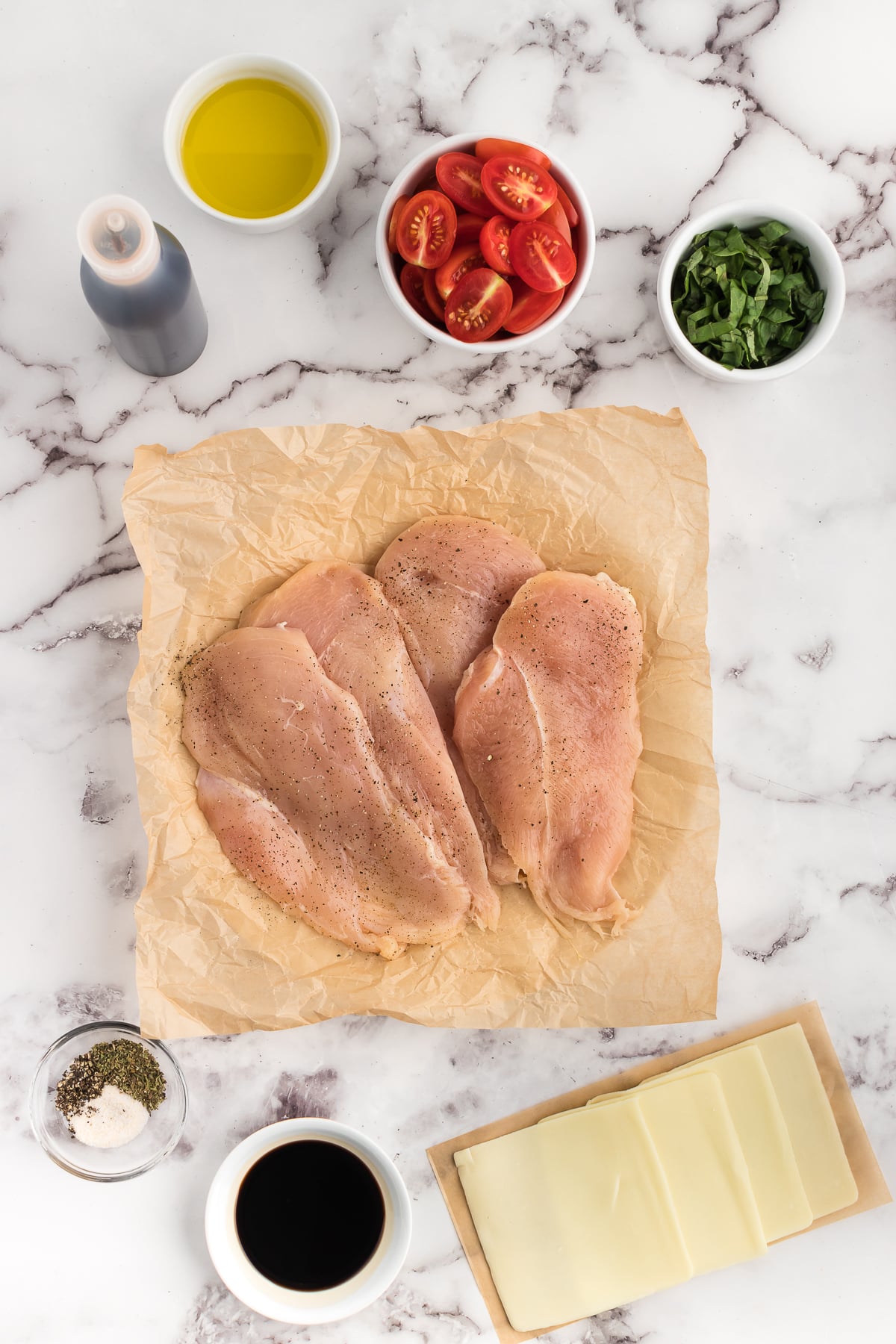 ingredients for chicken caprese bake on a white marble counter top