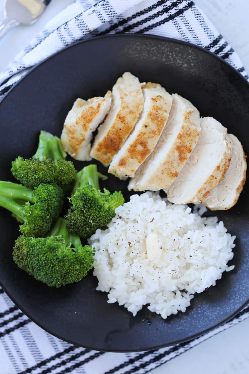 air fryer frozen chicken breast after cooking on a black plate on a black and white background, horizontal photo top down view