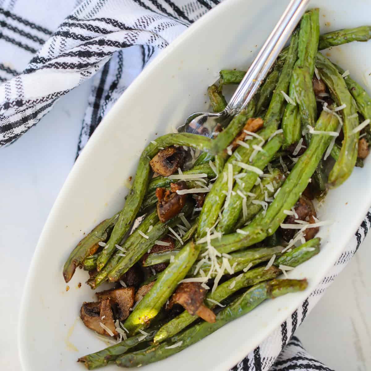 air fryer green bean with mushroom recipe in a white bowl sprinkled with parmesan
