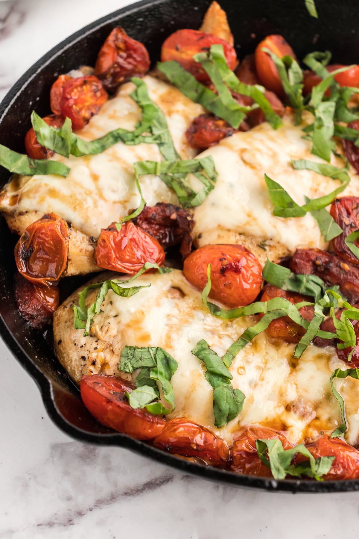 caprese chicken bake close up of the chicken cutlets  with balsamic tomatoes and basil