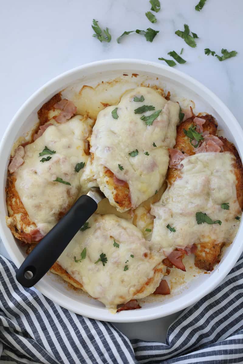 a chicken cordon bleu keto recipe with a mustard cream sauce on a white background with a black and white cloth