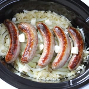 laying the crockpot brats on top of the sauerkraut and dotting with butter