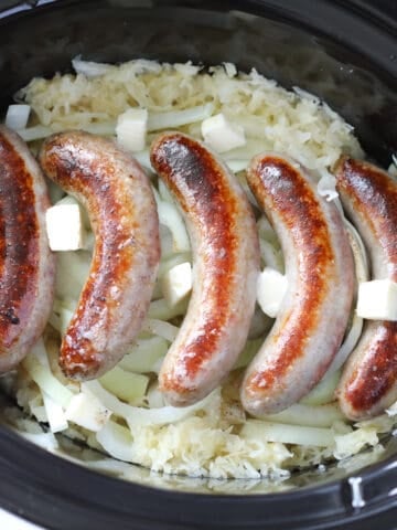 laying the crockpot brats on top of the sauerkraut and dotting with butter