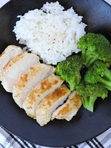 frozen chicken breast air fryer recipe after cooking served sliced on a plate with broccoli and rice