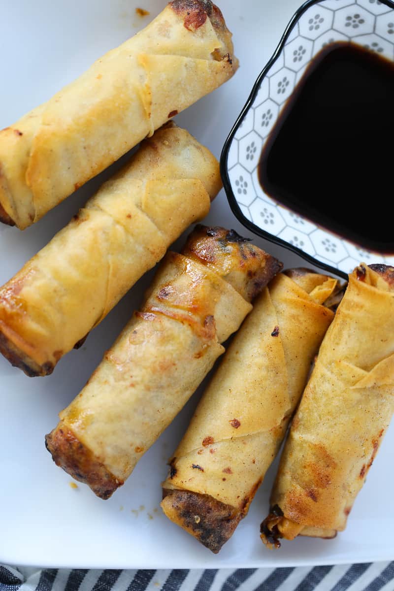 making frozen egg rolls in air fryer on a plate after cooking with sauce on the side