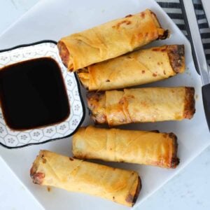 frozen egg rolls in air fryer on a white plate with soy sauce