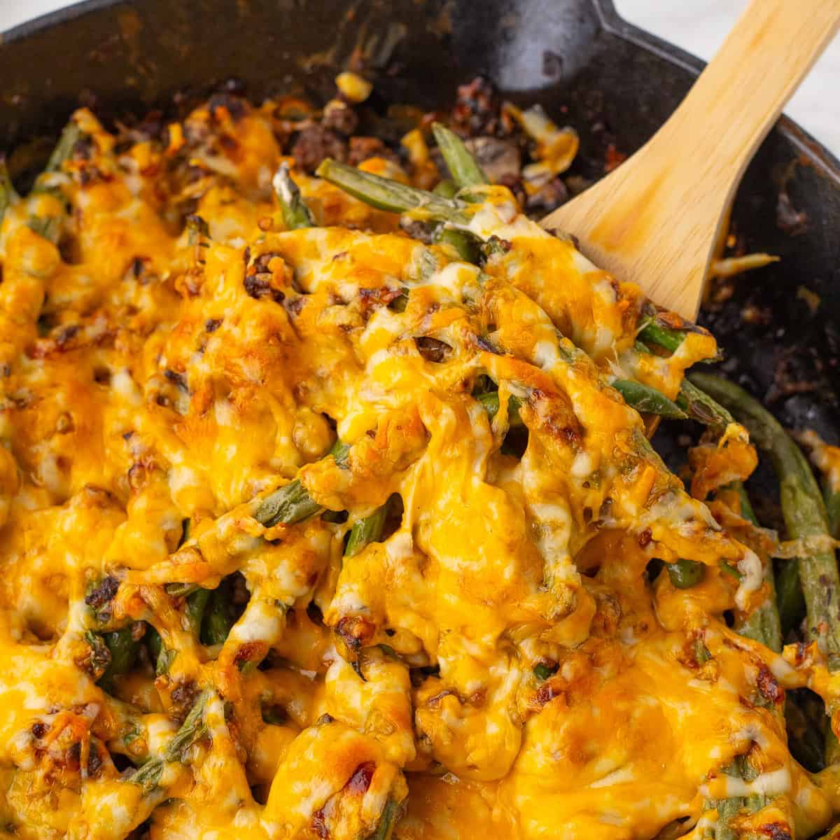 close up of the green bean beef casserole on a wooden spoon