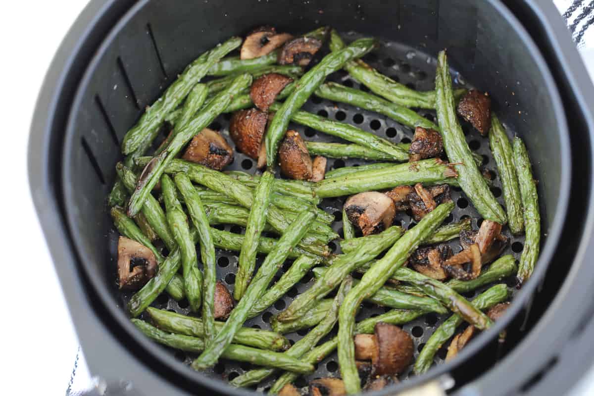 green beans in air fryer basket with mushrooms right after getting cooked