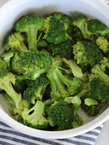 how to steam broccoli in the microwave, photo after cooking with lemon served on the side in a white dish