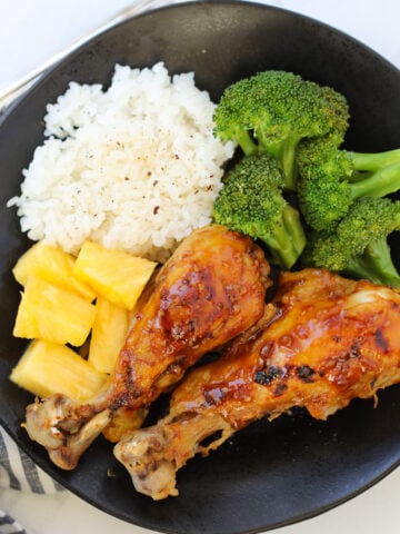 instant pot chicken drumsticks on a black plate with broccoli and rice