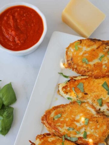 keto parmesan crusted chicken with sauce on a white plate