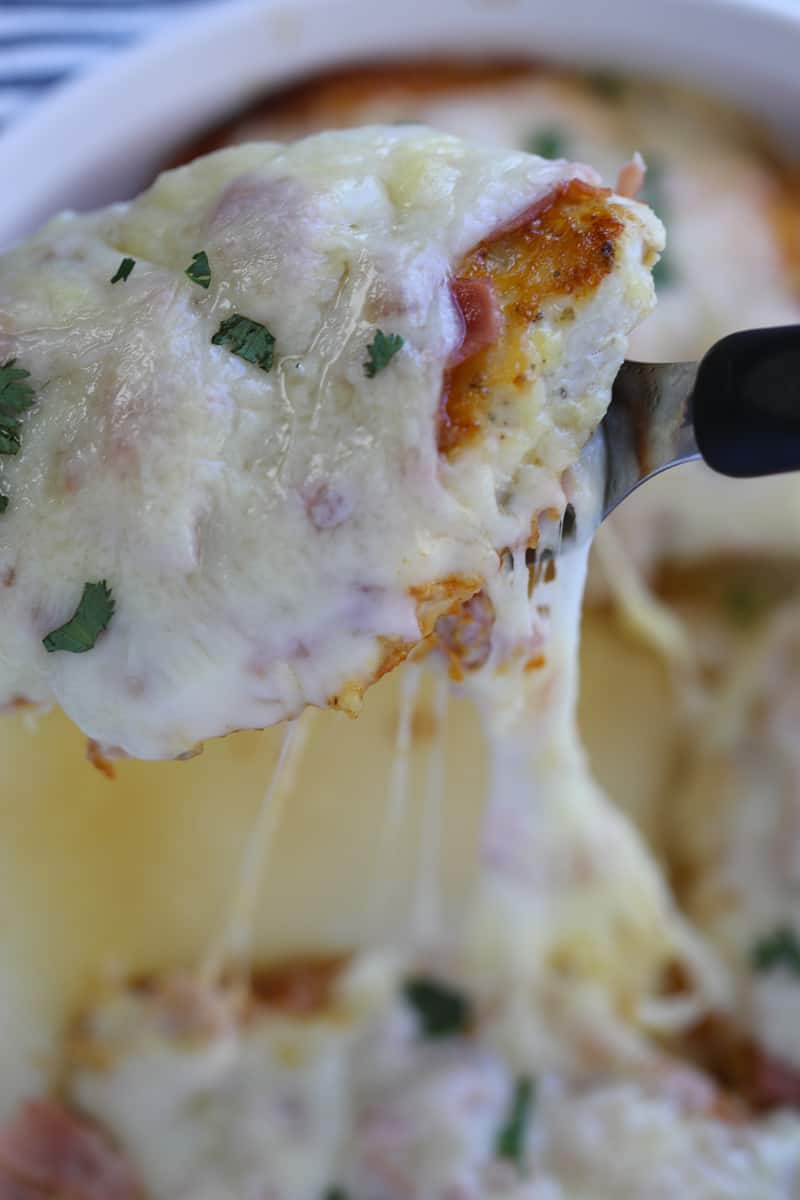 low carb chicken cordon bleu cheese pull lifting a chicken breast out of the pan