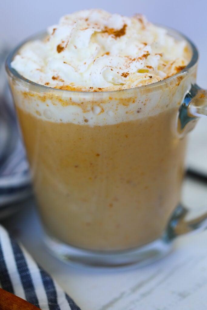 sugar free pumpkin spice latte in a clear mug loaded with whipping cream