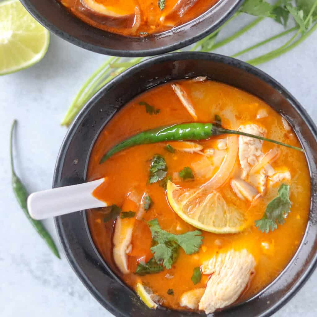 thai coconut chicken soup in a black bowl on a gray background