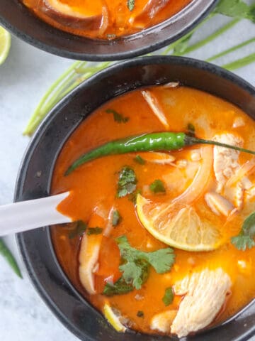 thai coconut chicken soup in a black bowl on a gray background