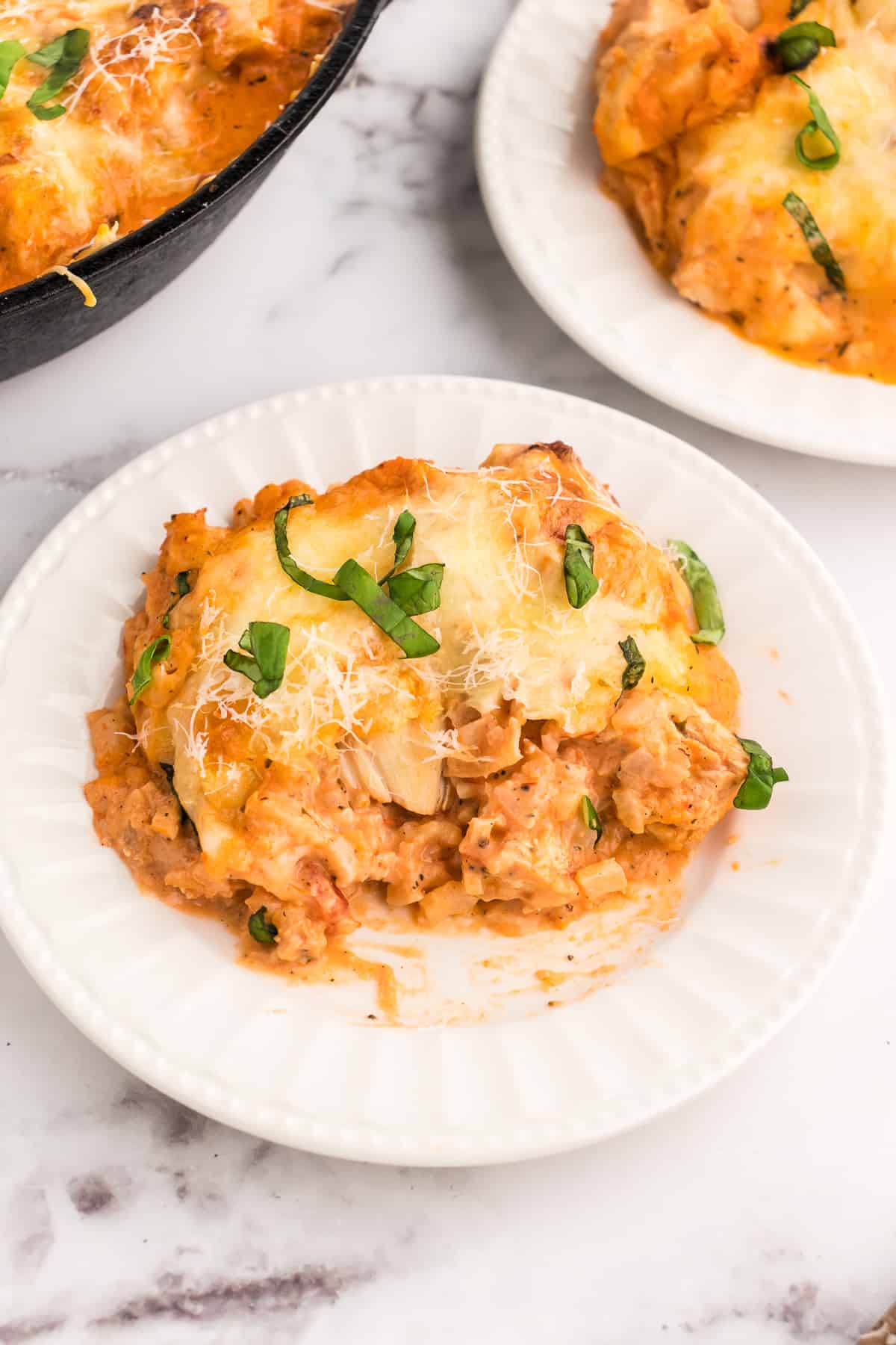 baked chicken parmesan casserole with a serving on a white plate