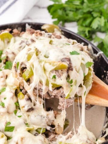 a spoonful of cheesy philly casserole dripping off ready to serve