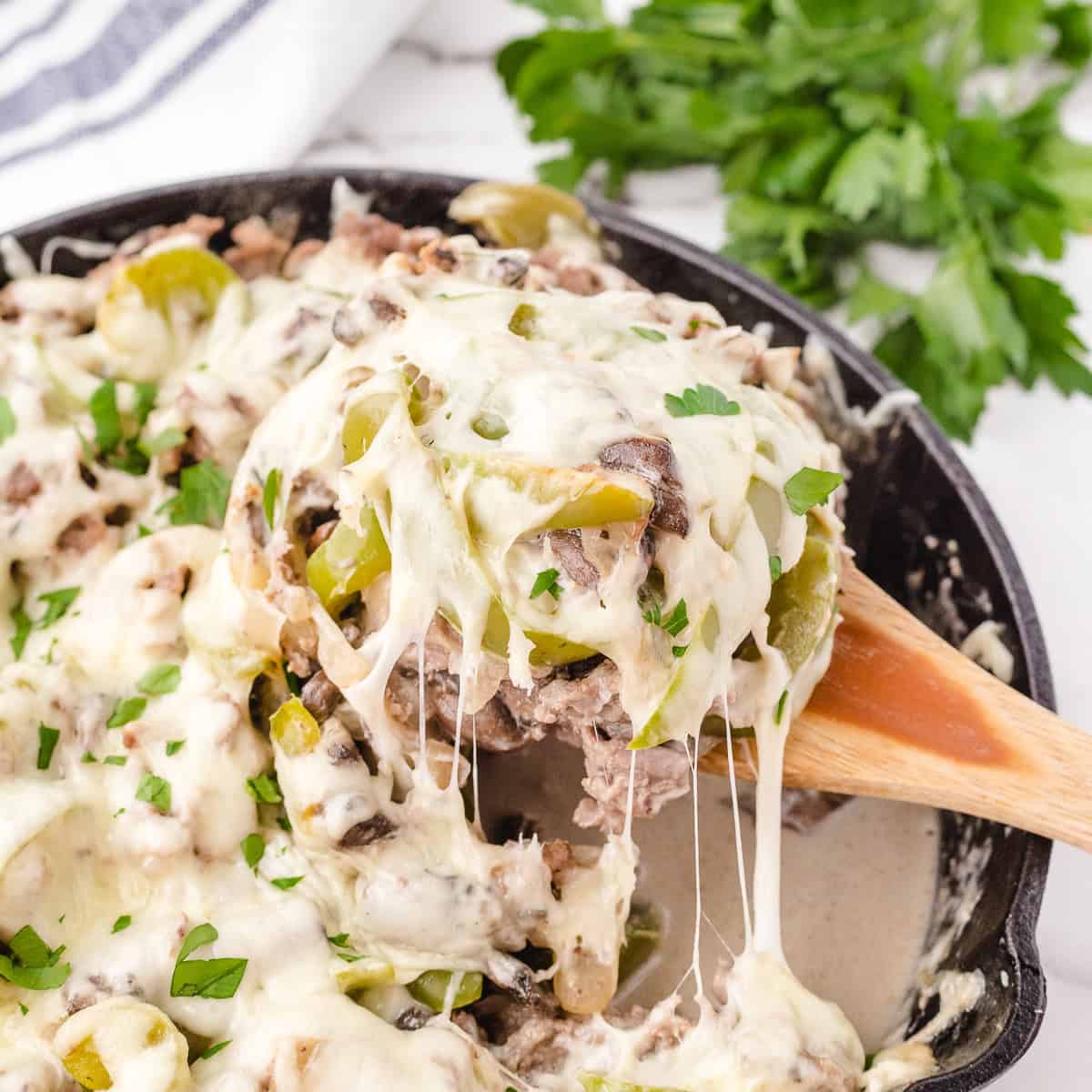 a spoonful of cheesy philly casserole dripping off ready to serve