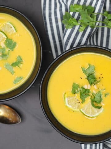 paleo butternut squash soup in a bowl with cilantro and limes