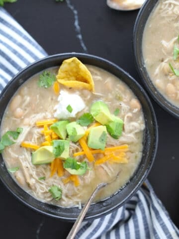 black bowls on a black background of white chicken chili instant pot dishes