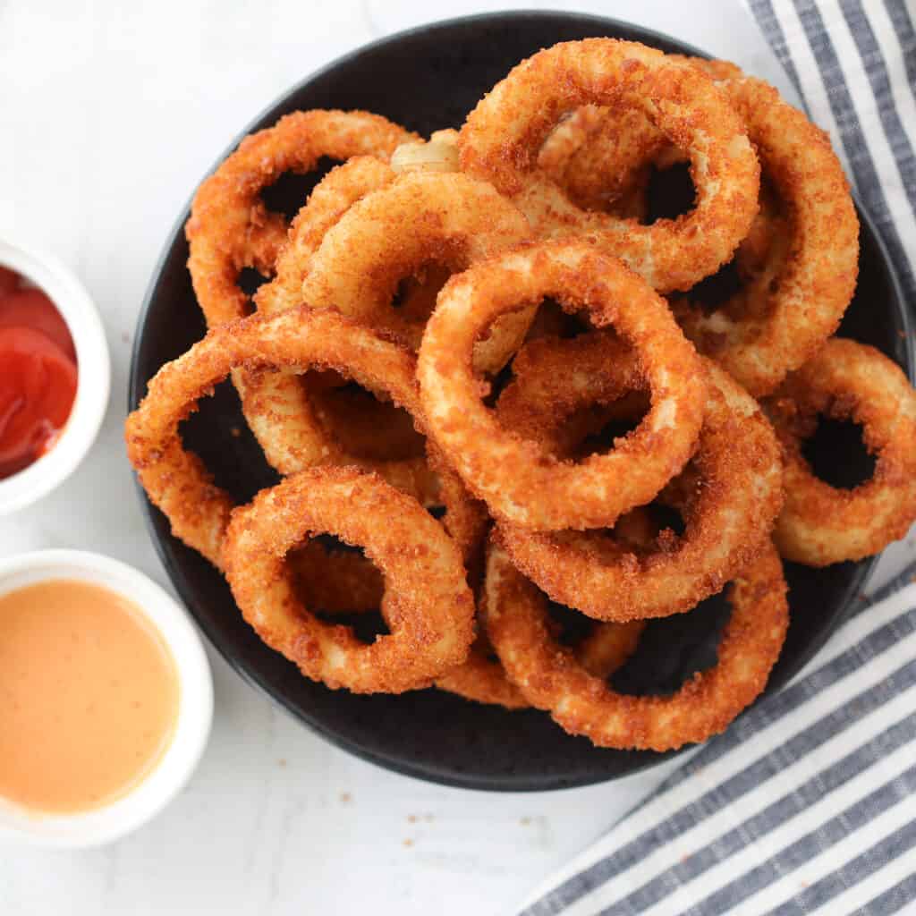air fryer frozen onion rings on a black plate after cooking