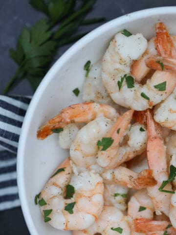 air fryer frozen shrimp with garlic butter in a white bowl on a black background
