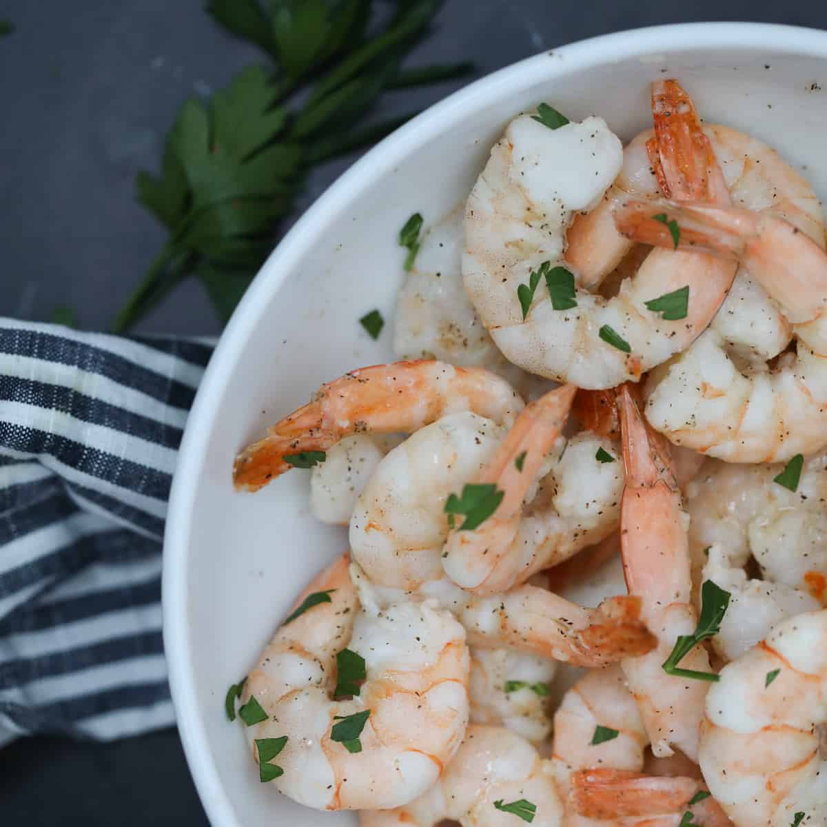 air fryer frozen shrimp with garlic butter in a white bowl on a black background