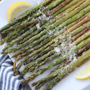 asparagus in air fryer topped with parmesan on a white plate