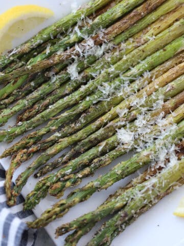 asparagus in air fryer topped with parmesan on a white plate